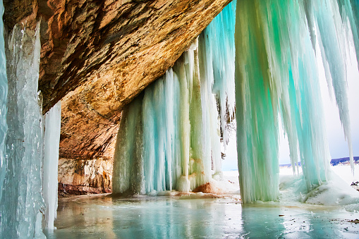 Image of Cave entrance in winter covered in large blue and green icicles