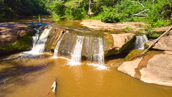 Image of Close view of waterfall over large boulder with brown water