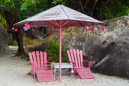 Wooden pink umbrella and chairs on tropical beach in Khanh Hoa, Vietnam