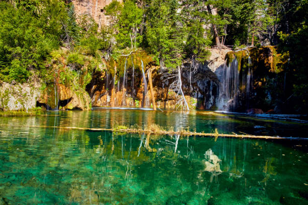 istock Crystal clear teal lake with waterfall over mossy rocks 1490085200