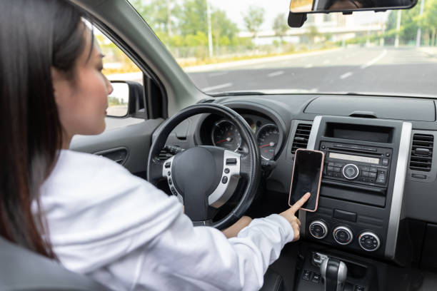 istock Side View Of Young Woman Using Mobile Phone While Driving Car 1490085385