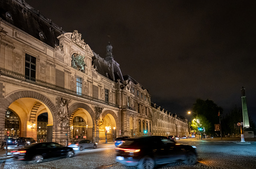 Paris, France. 7 May 2023. Cars on a road outside the Louvre building in Paris at night.