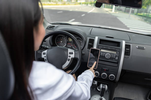 istock Side View Of Young Woman Using Mobile Phone While Driving Car 1490085671