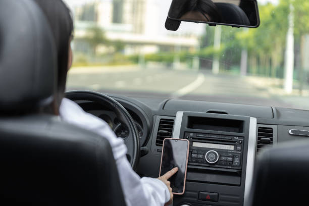 istock Side View Of Young Woman Using Mobile Phone While Driving Car 1490087095