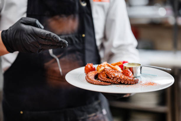 istock Professional chef garnishing an octopus dish in commercial kitchen 1490088622
