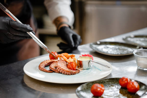 istock Professional chef garnishing an octopus dish in commercial kitchen 1490088626