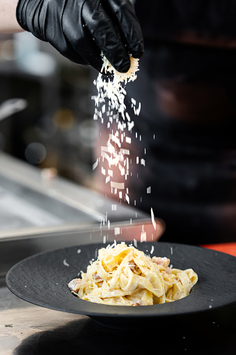 Professional chef preparing tasty pasta carbonara in commercial kitchen