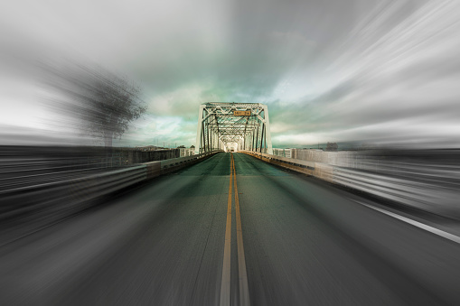 Rural highway approaching a bridge in Llano, Texas with motion blur.