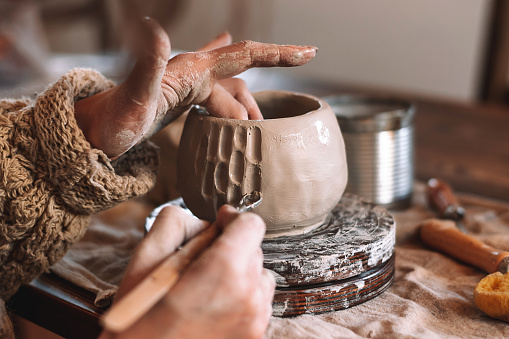 Female sculptor making clay mug in a home workshop,hands close-up.Small business,entrepreneurship,hobby, leisure concept.