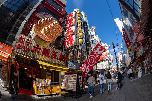 Osaka, Japan - August 19, 2022 : People walk through the Dotonbori district of Osaka, Japan. Dotonbori district is a famous tourist destination in Osaka, Japan. Many restaurants are located in Dotonbori district.