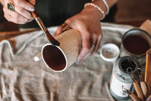 istock Female sculptor making clay pottery in a home workshop,glazing a clay mug,hands close-up.Small business,entrepreneurship,hobby, leisure concept 1490101345