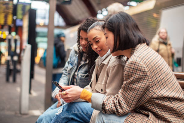 istock Group of female friends using a phone at a train station 1490102978