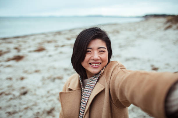 istock Young Asian woman taking a selfie on a beach 1490103158