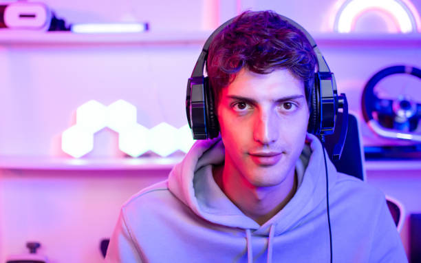 istock Portrait handsome young male game online streamer, caster, smiling, looking at camera, compete games, sitting in room with decorated neon light. Looking at computer. 1490106799