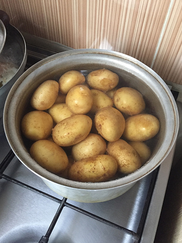 Potatoes boiling in water in cooking pan
