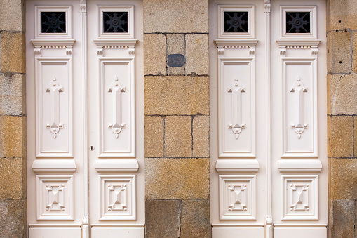 Close up view of two closed white carved wooden front doors . Stone house . Pontevedra province, Galicia, Spain.
