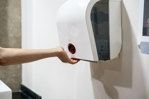 Young boy dries wet hands with an electric hand dryers