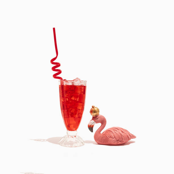 白い背景に冷たいさわやかな赤いカクテルとアイスキューブ、ピンクのフラミンゴ、ストローのグラス。 夏の飲み物、パーティーシーン。トレンディなミニマリストの休暇の構成。 - drink umbrella cocktail glass isolated ストックフォトと画像