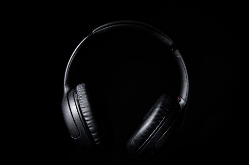 Still life of professional wireless headphones floating in the air on a black background.