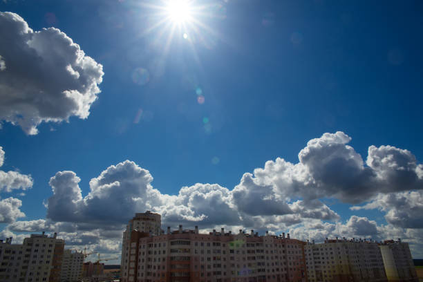 Deep blue skies with white clouds background and modern multi-storey residential area on the horizon, blue cloudy skies texture, dark blue sky wallpaper with white fully clouds and sunlight.