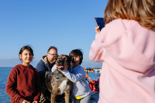 family with dog posing for photos taken by other child with mobile