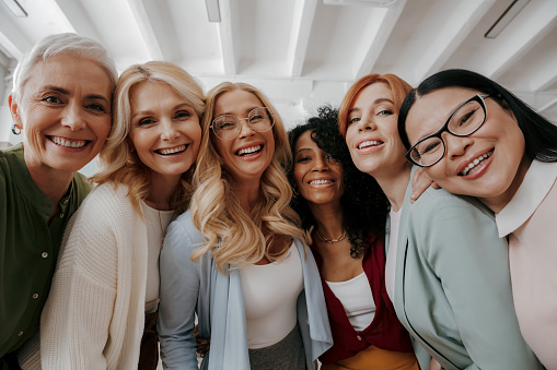 Low angle view of multi-ethnic group of mature women embracing and smiling at camera