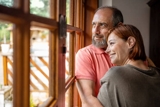 istock Beautiful mature couple standing by bedroom window 1490127464