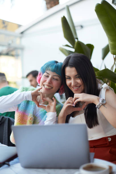 istock Two close friends are making a heart sign with their hands while videoconferencing with another friend over the computer. 1490128884