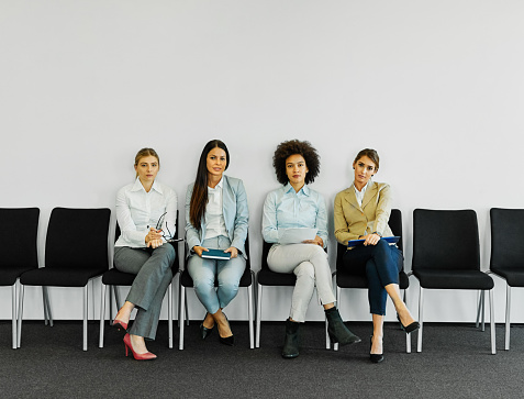 Group of young businesswomen sitting in chairs and waiting for an interview