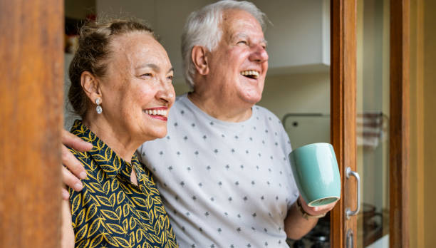 istock Smiling senior couple standing at window with cup of coffee 1490129520