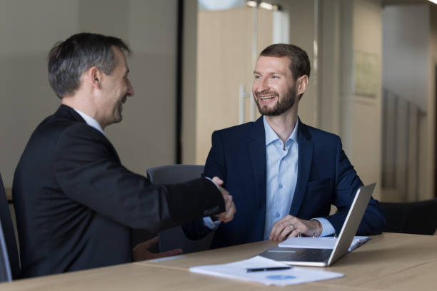 istock Happy younger and elder business professional men shaking hands 1490130214