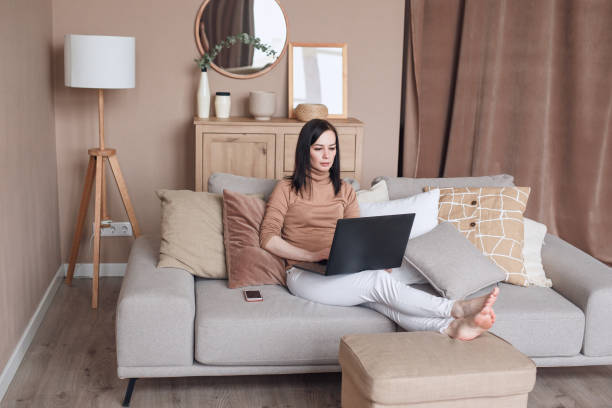 istock Relaxed female on sofa with laptop working at home 1490132378