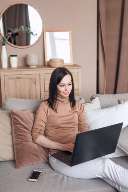 istock Woman work at the notebook sit down on the sofa at home 1490132486