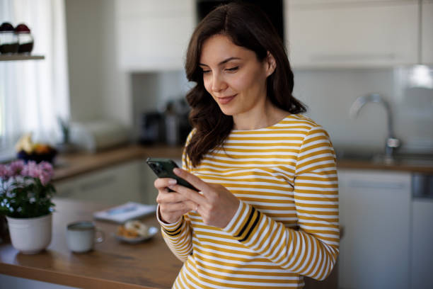 istock Young smiling woman with mobile phone in kitchen 1490133723