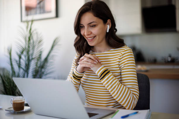 Young smiling woman with bluetooth headphones having video call at home - fotografia de stock