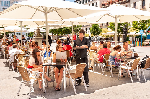 Madrid, Spain - June 4, 2012: People ordering drinks at bar tables on Plaza de Santa Ana, Barrio de las Letras