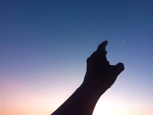 istock Silhouette of A Left Hand Reaching for the Moon into the Sky 1490140630