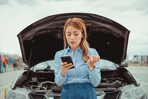 Woman with smartphone caling autoservice because of car problem. Accident and breakdowns with auto concept.