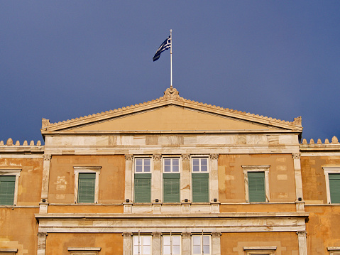 Greek parliament (Syntagma) facade with greek flag on top, Athens, Greece