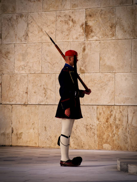 Athens-Greece/  7 September 2025:  Single Guard (Evzones) looking away. Standing in front of the war memorial. Tomb of  unknown soldier, and part of  the Guardhouse.