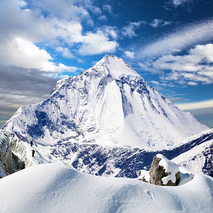 mount Dhaulagiri with a snowdrift, a glacier and two climbers, Nepal Himalayas mountains