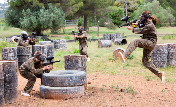 Group of people in full gear playing paintball on shooting range outdoor Group of people in full gear playing paintball on shooting range paintball photography stock pictures, royalty-free photos & images