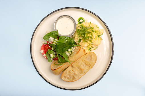 Tasty diet dish for breakfast or lunch. Scrambled eggs on plate over blue background. Healthy food. Top view, flat lay