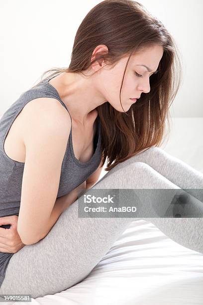 Young Woman In Gray Clutching Her Stomach In Pain Stock Photo - Download Image Now - Abdomen, Adult, Beautiful People