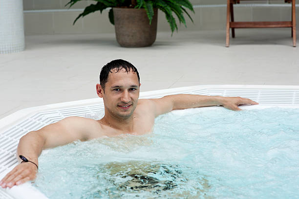 man in indoor hot tub stock photo
