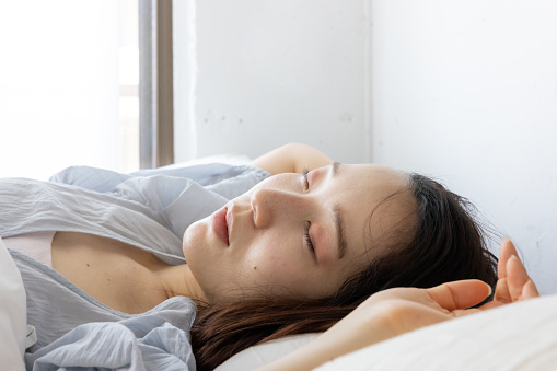 Young woman sleeping on bed in the morning