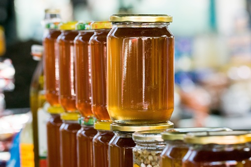 A row of natural jars of honey for sale at the stall of a green market vendor in Tetovo, North Macedonia in the former Yugoslavia. Dark yellow colour.