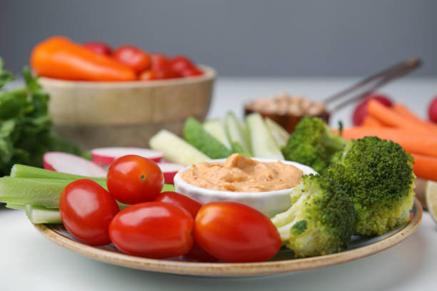 istock Plate with delicious hummus and fresh vegetables on white table, closeup 1490188455