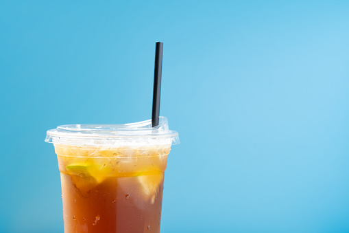 side view cup of iced lemon with straw horizontal composition