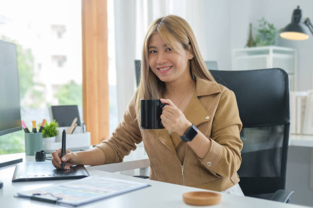 Charming young creative woman sitting at her workplace and smiling to camera.